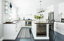 Kitchen island with wine cooler and bar stool in white kitchen dark floor