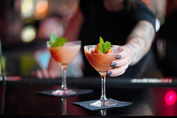 A bartender serving cocktails at a bar
