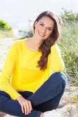 A brunette woman wearing a yellow jumper and jeans