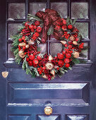 Christmas wreath on grey door with golden pears and red apples fruits and berries