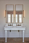 Vintage-style washstand with twin sinks, two mirrors and three wall lamps in bathroom