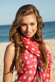 A young blonde woman by the sea wearing a beach towel