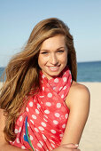 A young blonde woman by the sea wearing a beach towel
