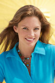 A young brunette woman wearing a blue shirt in front of a yellow parasol