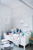 Himmelbett mit gepunkteter Bettwäsche und Stofftieren in hellem Kinderzimmer