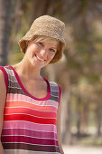 A mature blonde woman with short hair outside wearing a striped top and a hat