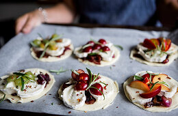 Frau hält Backblech mit ungebackenen Minipizzen