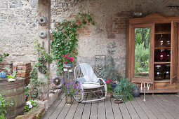 Large storage jars in wooden cupboard and rocking chair on roofed terrace