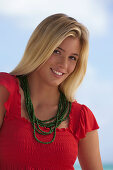 A young blonde woman on a beach wearing a red top
