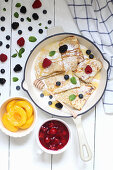 Pancakes with berries and honey served with peaches and red fruit jelly