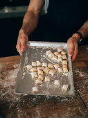 Hände halten Backblech mit selbst gemachten Gnocchi