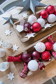 Rote und weiße Christbaumanhänger in Holztrögen auf dem Tisch