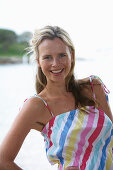 A young blonde woman on a beach wearing a light-blue top