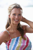 Junge blonde Frau im gestreiften Top am Strand