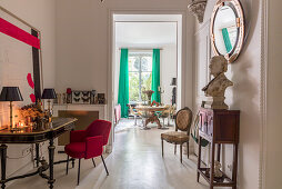 Bust on console table below mirror on wall, red upholstered chair and antique table in anteroom