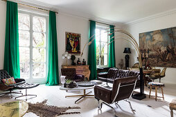 Brown leather sofa set and Italian designer lamp in living room with huge painting in dining area in background