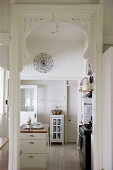 Blick durch einen Türbogen in die weiße Landhausküche