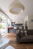 View past sofa into kitchen with counter and bar stools in open-plan interior