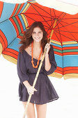 A brunette woman wearing a purple bath robe with a colourful parasol