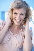 A blonde woman wearing a pink short-sleeved blouse