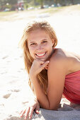 Junge blonde Frau im rosa Top am Strand