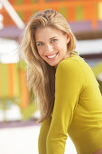 Junge blonde Frau mit olivfarbenem Shirt am Strand