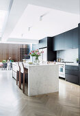 Stone kitchen island in open kitchen with herringbone parquet