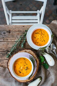 Kürbiscremesuppe mit Kräutern auf rustikalem Holztisch (Aufsicht)