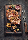 Grilled t-bone steak on serving board and fork