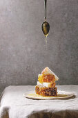 Organic honey in honeycombs and flowing honey from spoon to slices of wheat bread in spotted ceramic plate