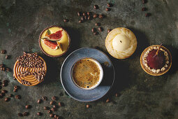 Variety of sweet tartlets with chocolate, caramel, pears, figs with cup of coffee and coffee beans