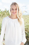 A young blonde woman wearing a white blouse