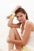 A brunette woman on a beach wearing a white top and shorts