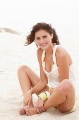 A brunette woman on a beach wearing a white top and shorts