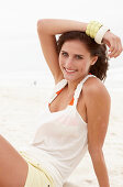 Brünette Frau in weißem Top und Shorts am Strand