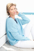A mature woman wearing a blue jumper and white trousers