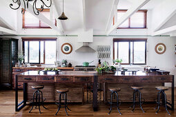 Kitchen island with drawers made from recycled wood and vintage bar stools in an open kitchen