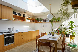 Esstisch mit Stühlen und Zimmerpflanzen in offener Küche mit Oberlichtfenster