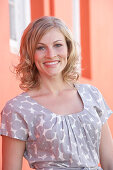 A blonde woman wearing a grey spotted blouse