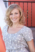 A blonde woman wearing a grey spotted blouse