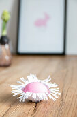 Easter egg in handmade paper nest on wooden surface
