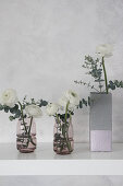 Ranunculus in concrete-effect vase handmade from milk carton and glass vases