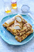 Thin pancakes stuffed with cottage cheese a jar of honey on blue plate