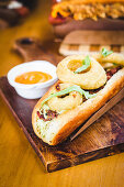 Hot Dog mit Fleischfüllung und frittierten Zwiebelringen