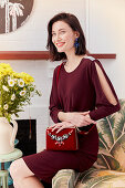 Brünette Frau im bordeaux-roten Abendkleid und Handtasche