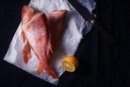 Raw uncooked fish perch on black background with lemon