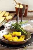 Fried polenta slices with rosemary in a vintage pan