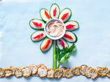 Creative flower made of vegetables as the petals and stalk with rice crackers as the ground