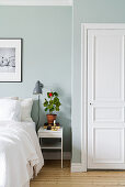 Geranium on bedside table against pale blue wall in bedroom