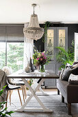 Beaded chandelier above dining table in front of display case and window